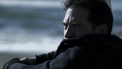 Sad angry man in front of the ocean turning around looking camera slow motion Stock Footage 107489005