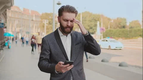 Sad attractive bearded man use phone walking on city street. Nervous angry Stock Footage 140479144