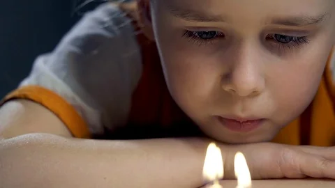 Sad baby girl gently blows out the candles close-up of fire and smoke Stock Footage