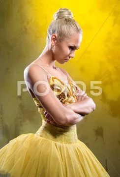 Sad ballerina in yellow tutu posing over obsolete wall Stock Photos