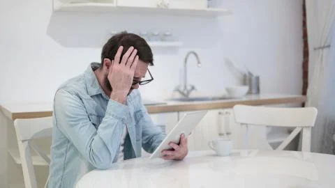 Sad Beard Young Man Facing Loss on Tablet Stock Photos