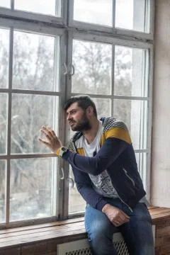 Sad bearded man looking through the window Stock Photos