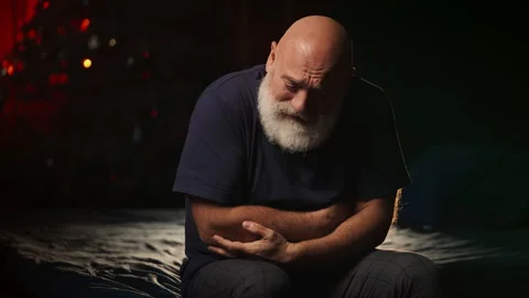 Sad bearded middle-aged man suffers abdominal pain while sitting on bed Stock Footage 346714297