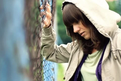 Sad beautiful woman by chain-link fence, outdoors NTSC Stock Footage