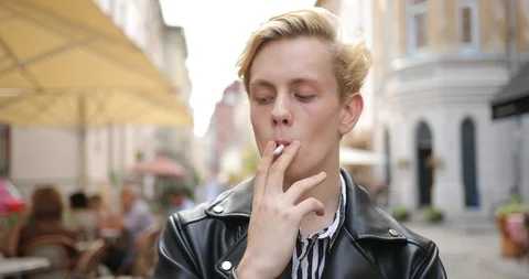 Sad blond guy stands and smokes on the street Stock Footage 126576893