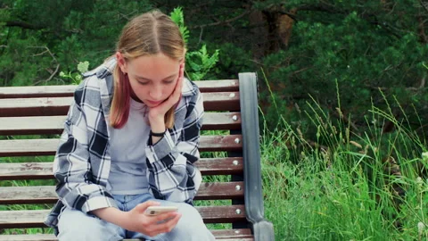 Sad boring teen girl sitting on bench in... | Stock Video | Pond5
