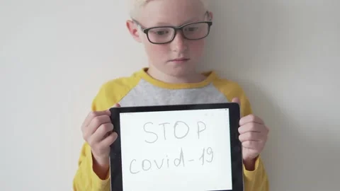 Sad Boy boy with glasses holding the inscription STOP Covid-19 Stock Footage 134588154