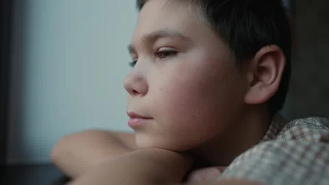 Sad boy looking outside the window Stock Footage 241437983