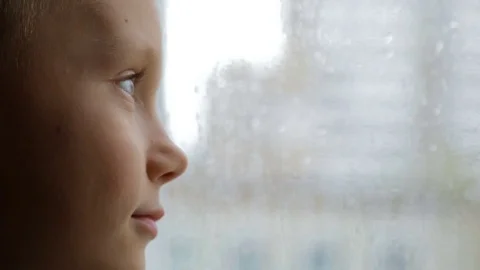 Sad boy looks out the window in rainy weather Vídeo Stock 81067185
