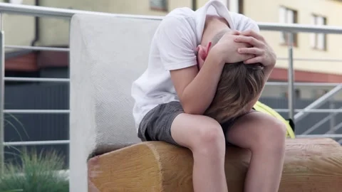 Sad boy sits in a bad mood near his house after school. Childhood depression. Stock-Footage 289841662