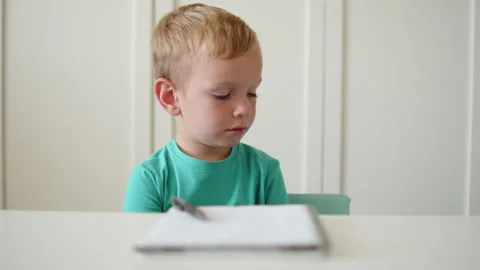 Sad boy sitting behind a desk. Kid doesn't want to learn and do homework in.. Stock Footage 340728224