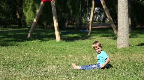 Sad boy sitting on the grass Видео 52436908