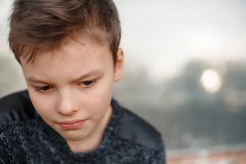 Sad boy is sitting next to the wall. Stock Photos