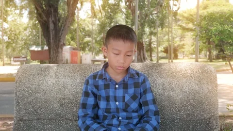 A sad boy is sitting at the park alone. Stock Footage 118875345