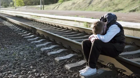 Sad boy sitting on the railway in a bad mood after school. Childhood bullying. Stock Footage 312095083