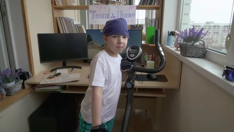 Sad Boy Standing Next To Exercise Bike And Looking out Window Wanting To Go F Stock Footage 129586873