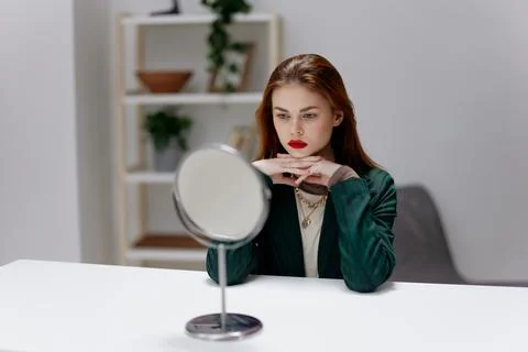 A sad, brooding, tired young red-haired woman at the table is thinking about a Stock Photos