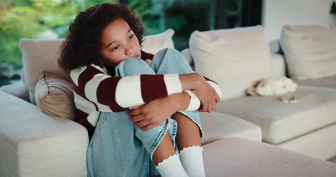Sad, child and thinking on couch, home and girl with low self esteem from Stock Footage 335525790