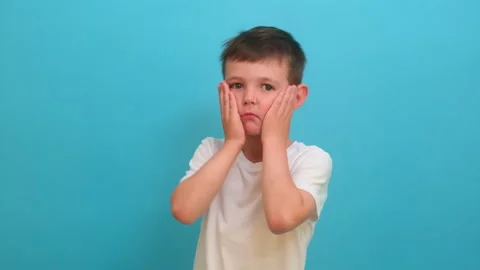 Sad child boy holds hands on cheek due to toothache. Experiencing dental pain or Stock Footage 340407192
