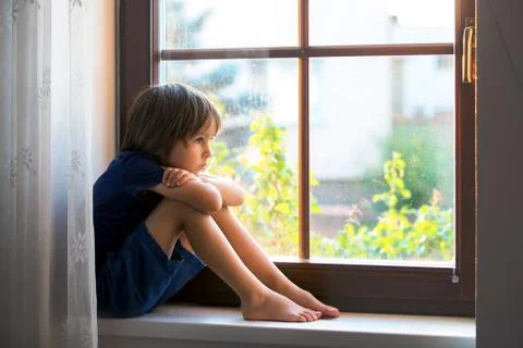 Sad child, boy, sitting on a window shield Stock Photos