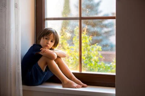 Sad child, boy, sitting on a window shield Stock Photos