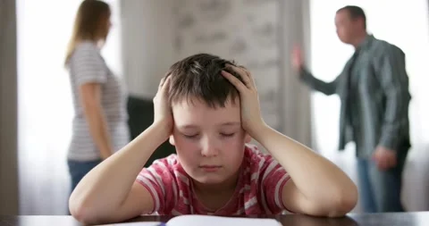 Sad child covers his ears with his hands during an argument between his parents Stock Footage 238771635
