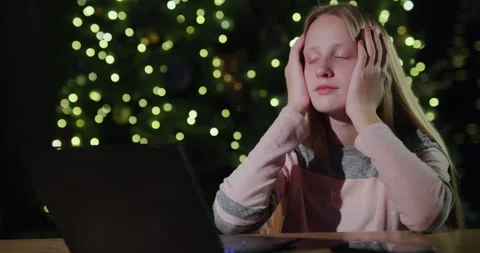 Sad child looking at laptop screen against background of blurry Christmas tree Stockbeeldmateriaal 251316795