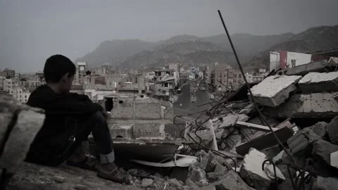 A sad child sits on the rubble of destroyed houses due to the Yemen war Vídeo Stock 158573147