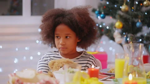 Sad child sitting with teddy bear at Christmas dinner table while parent argue Stock Footage 166873290