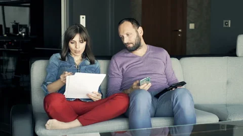 Sad couple counting bills and worrying about money on sofa at home Vídeo Stock 63218520