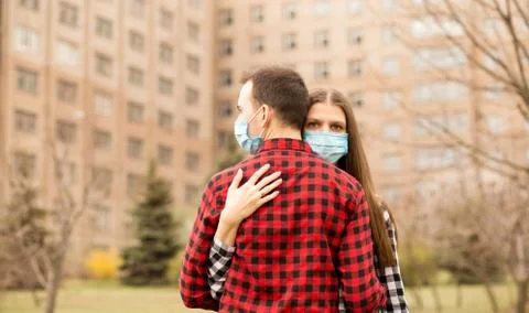 Sad couple in love, man and woman hug each other in protective medical mask o Stock Photos