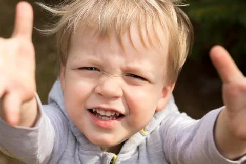 Sad crying toddler pulls his hands up. Close up portrait of baby boy asking for Stock Photos