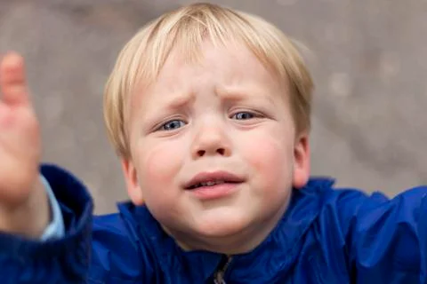 Sad crying toddler pulls his hands up. Close up portrait of baby boy asking for Stock Photos