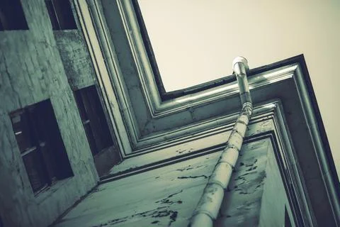 A sad, dark image of a corner of a dilapidated building with a drainpipe and  Stock Photos