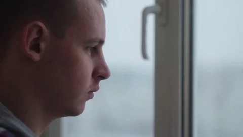 Sad depressed man drinking tea by the window in home Stock Footage 70899180