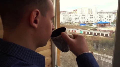 Sad, depressed man drinking tea by the window in home Stock Footage 74752346