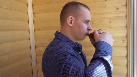 Sad, depressed man drinking tea by the window in home Stock Footage 75210840