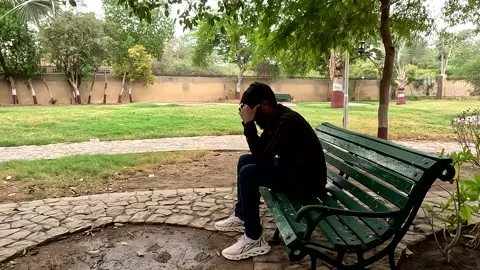 Sad depressed young man sitting alone on park bench praying with anxiety Stock Footage 343263956