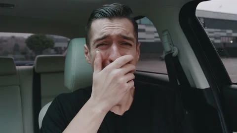 Sad desperate man crying while sitting in the car. Shocked man crying upon