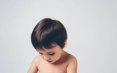 Sad, disoriented child looks down on a white background. The gill or boy has Stock Photos