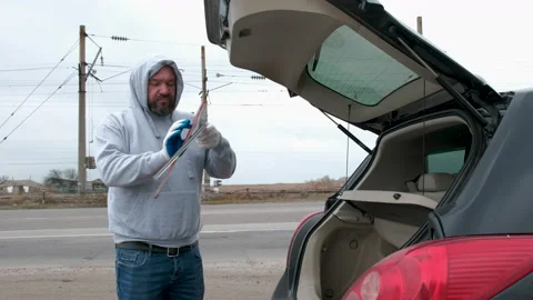 Sad driver of a broken car. Collects red triangular sign Stock Footage 154060282