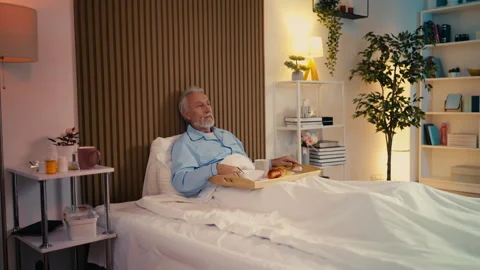 Sad elderly bedridden man refusing to eat a meal at a retirement facility Stock Footage 279177570