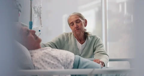Sad, elderly couple and holding hands by hospital bed to support cancer patient Stock Footage 310795236