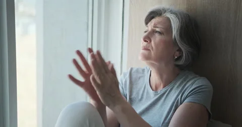 Sad elderly lady staring out the window, lonely in her old age. Stock Footage 159980696
