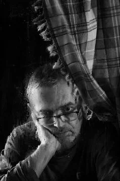 Sad elderly man looking out the window. Stock Photos