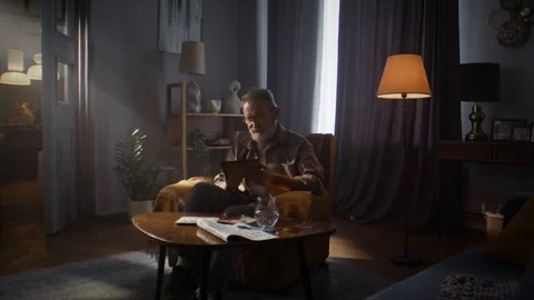 Sad elderly man sits alone in room staring at framed photograph Stock Footage 315368498