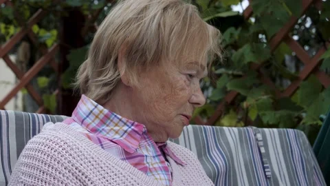 Sad Elderly Woman Looks Down And Takes A Deep Breath From Frustration Vidéo 219324792