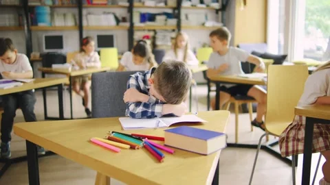 A sad elementary school student in a blue plaid shirt is being fussy, crying Stock Footage 279518861