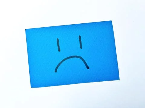 Sad face expression drawn on blue paper card isolated on white background Stock Photos
