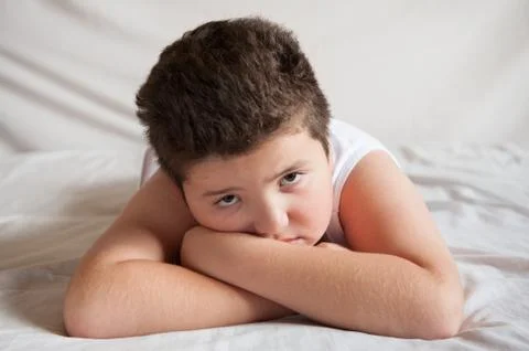 Sad fat boy lying on the bed Stock-Fotos